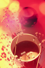 Soft blurred and toned. Cup of coffee  in morning time.  Soft sunlight bokeh. Vintage filter style. Boho still life with red cup and flowers.