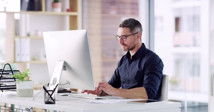 Resolving client complaints via email. 4k video footage of a handsome mature businessman sitting alone in his office and using his computer.
