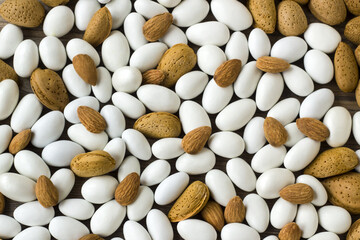 Traditional, white colored, chocolate covered almond candies with almonds nuts on wooden surface,fulled frame