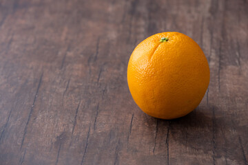 Fresh whole orange on a wood background with room for copy
