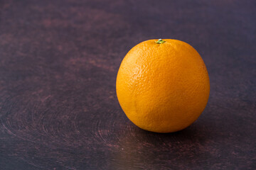 Fresh whole orange on a moody purple background with room for copy
