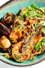 Japanese soba with seafood cooked on wok in asian style on white background. Noodle seafood in ceramic bowl. Indonesian wok with prawn, mussels and soba noodles. Spicy thai dish with shrimp and udon.