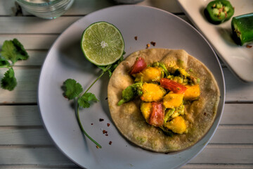 Top view of tacos with mango, avocado, jalapeno, tomato and red onion