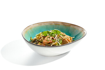Pan asian food - chicken udon with mushrooms on white background. Noodle with chicken  on wok in asian style. Indonesian wok with black udon noodles and chicken in ceramic bowl.