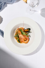 Risotto with seafood in contemporary style on white background. Italian risotto with prawn, mussels, squid in frutti di mare style. Summer dining with seafood and rice. Summer day seafood concept.