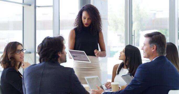 She knows how to delegate tasks as a leader. 4k video footage of a businesswoman using a digital tablet while giving a presentation to her colleagues in a modern office.