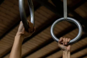 Foto op Canvas Latin American woman hands holding gymnastic rings during her workout at the gym. Unrecognizable. Healthy Lifestyle Concept. © Amilciar