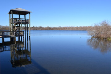Calm water surface of White Lake and wooden tower for bird watching, Cullinan Park, Sugar Land, Texas