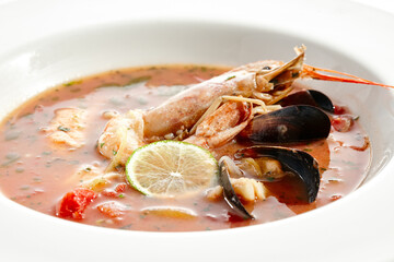 Tomato seafood soup in plate isolated on white background. Seafood stew Cioppino - shrimp,  mussels and salmon in tomato broth. Seafood dish in Italian restaurant menu.