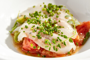 Healthy dinner - fish fillet with tomato and avocado on white plate. Diet food - cooked seabass on...