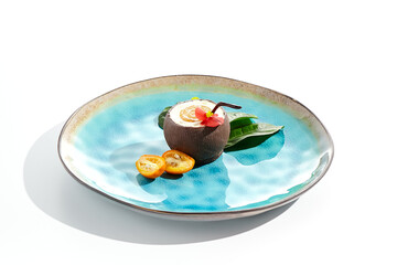 Creative summer dessert isolated on white background. Coconut from chocolate with mousse and passion fruit jelly. Coconut  and passion fruit cake in Hawaiian style. Dessert  in cocktail style.