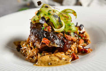 Braised beef cheeks with pearl barley and celery in creamy mushroom sauce. Veal cheek with mushroom risotto on gray stone background. Main course concept. Food menu for restaurant.