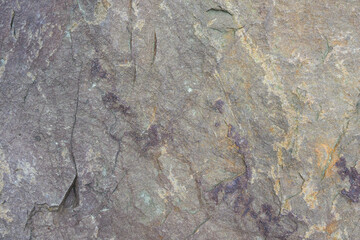 Rough cut rock in dark colors of gray and purple, as a natural  background
