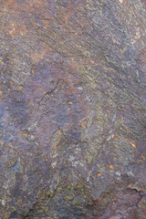 Rough cut rock in dark colors of gray and purple, as a natural  background
