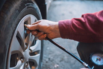 Mechanic checks tire pressure using pneumatic compressor with pressure gauge.