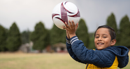 Boy ready to play holding a soccer ball in his hands
