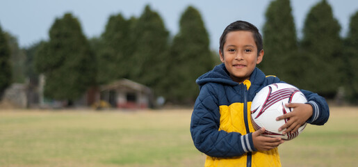 Boy ready to play holding a soccer ball in his hands