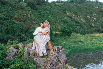 Romantic inloved couple sitting on rocks by the river.