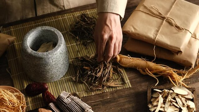 Top view of apocathery putting ingredient into mortar and pestle with chinese traditional medicine in wooden table 