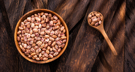 Phaseolus vulgaris - Dried pinto beans in the bowl and wooden spoon - obrazy, fototapety, plakaty