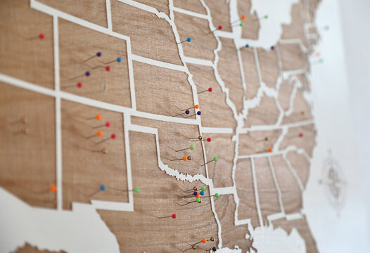 Wooden wall decoration as USA states map with colorful pins on it.