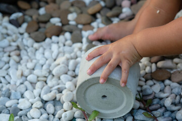 toddle hands play rocks and pot