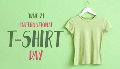 Hanger with green t-shirt on color background. International T-Shirt Day