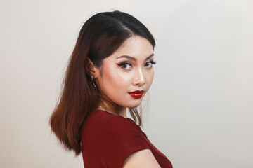 Naklejka premium A fierce-looking Asian woman in a red shirt side posing in front of white background