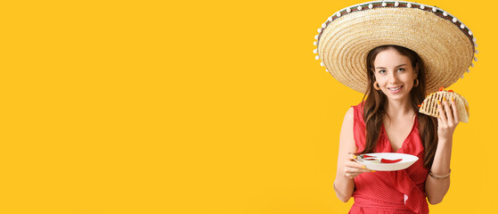 Beautiful young Mexican woman with tasty quesadilla and sombrero hat on color background with space...