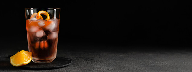 Glass of tasty Negroni cocktail on dark background with space for text