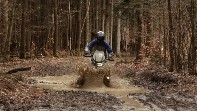 Off Road Motorbike Ripping Water Muddy Ponds, Extreme Sports Motocross rider driving in humid and brown forests in autumn rainy season trial
