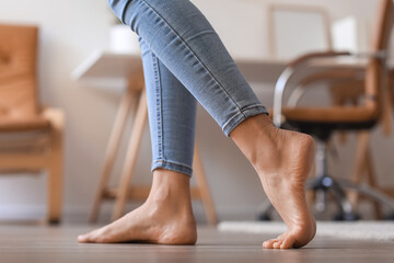 Bare feet of young woman walking at home, closeup