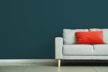Modern sofa with pillow near color wall in room