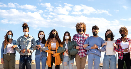 Panoramic of multiracial activists holding each others arms creating barrier wear face mask protesting on the street.