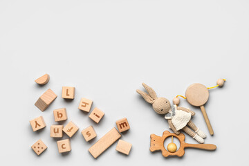 Wooden cubes with letters and baby toys on light background