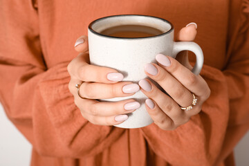 Woman with trendy manicure and stylish jewelry holding cup of coffee, closeup