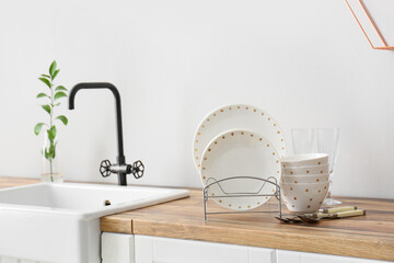 Beautiful dinnerware on wooden counter near light wall