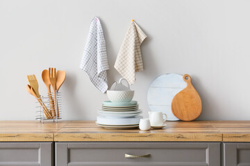 Beautiful dinnerware and kitchen utensils on counter near light wall