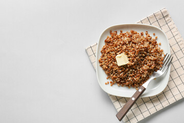 Plate of tasty buckwheat porridge on white background, top view