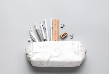 Pencil case with school stationery on light background