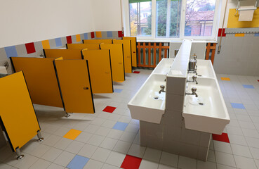 nursery bathrooms with the low ceramic sinks and the yellow toilet cubicles without children