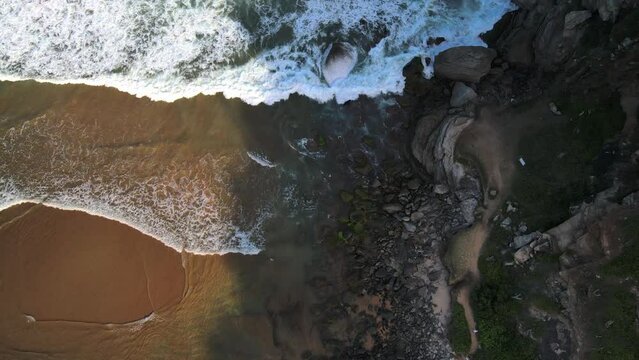 Aerial view of waves crashing into a rocky shoreline in Geriba Beach, Buzios, Brazil