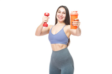 A beautiful, athletic, slim, smiling and cheerful woman holds a red dumbbell and a shaker with water. Lifestyle concept with sports and gym. Isolated on white background.