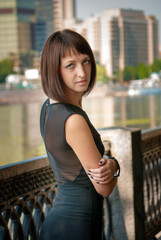 Young girl in black outdoor dress walking in the park in spring. On the background green forest. Perspective of space.