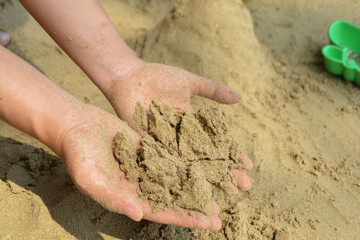 Sand in children's palms. On the beach. And building sand castle.