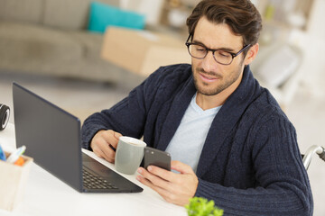man in wheelchair using a smartphone at home