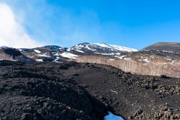 Solidified lava, ash and pumice on its slopes of snow covered craters. Yellow golden dry grass on...