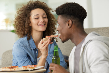 sweet young couple eating pizza at home