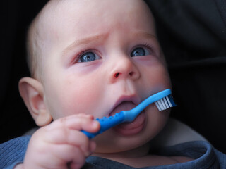 a toothbrush teether for newborn babies in the baby's mouth holds hands