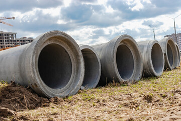 Reinforced concrete storm sewer pipes of large diameter stacked at a construction site. Sewer Large diameter pipes. Wastewater disposal in a modern city. - obrazy, fototapety, plakaty